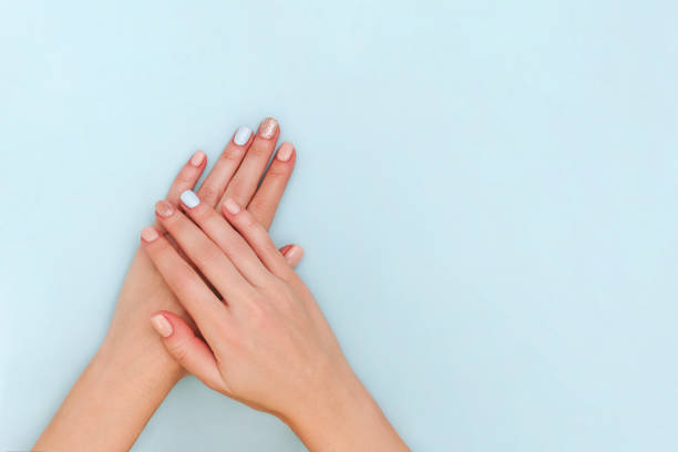 istock Woman's hands with pastel manicure on blue background. Copy space. 1162951376