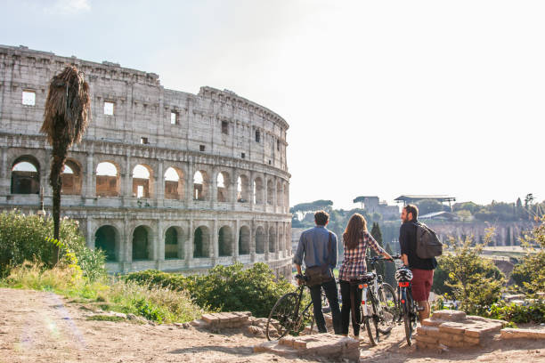 로마 콜로세움에서 자전거를 타는 세 명의 행복한 젊은 친구 관광객들이 즐거운 시간을 보내고 있습니다. - arch top 뉴스 사진 이미지
