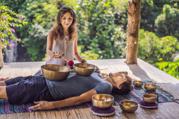 istock Nepal Buddha copper singing bowl at spa salon. Young beautiful man doing massage therapy singing bowls in the Spa against a waterfall. Sound therapy, recreation, meditation, healthy lifestyle and body care concept 1162952871