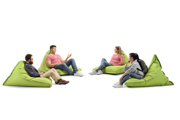 Vibrant yellow bean bag chair rests on wooden deck, surrounded by lush green grass. chair unique shape and bright color create cheerful and inviting atmosphere, perfect for relaxation