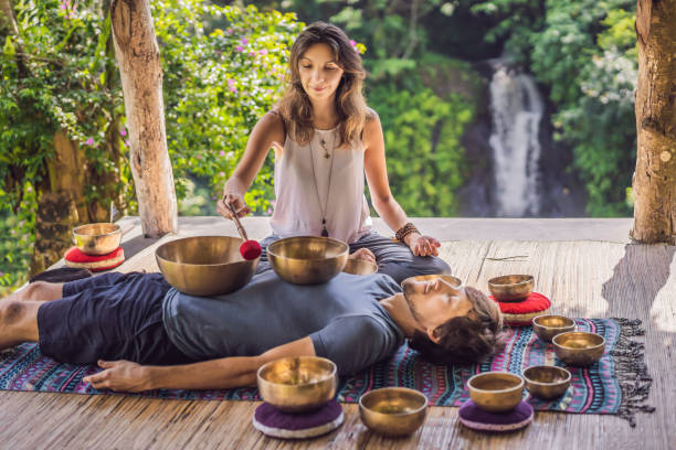 istock Nepal Buddha copper singing bowl at spa salon. Young beautiful man doing massage therapy singing bowls in the Spa against a waterfall. Sound therapy, recreation, meditation, healthy lifestyle and body care concept 1162959861