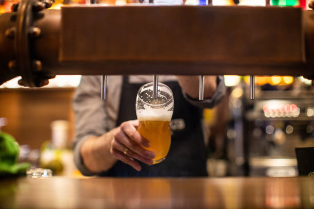 Unrecognizable Barista pouring a beer in a pub Unrecognizable man pouring a beer on beer tap in drinking glass, in a pub craft beer photos stock pictures, royalty-free photos & images