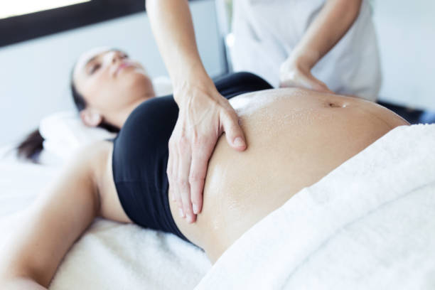 Female physiotherapist massaging tummy on pregnant woman in spa center. Close-up of female physiotherapist massaging tummy on pregnant woman in spa center. chiropractic adjustment photos stock pictures, royalty-free photos & images
