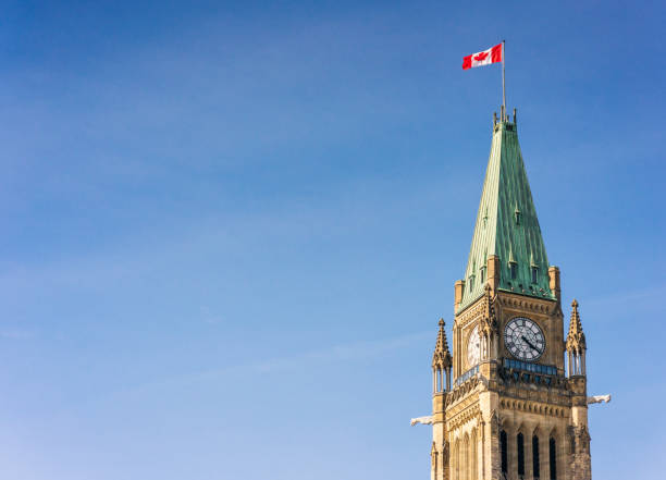 Peace Tower of Ottawa's Parliament Building A Canadian flag flying on the top of the Peace Tower, part of the Canadian Parliament Building in Ottawa. parliament building stock pictures, royalty-free photos & images