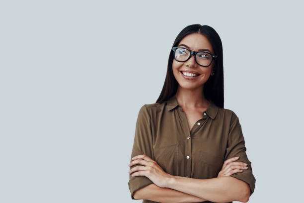 istock Thinking about... Attractive young Asian woman looking away and smiling while standing against grey background 1162963011