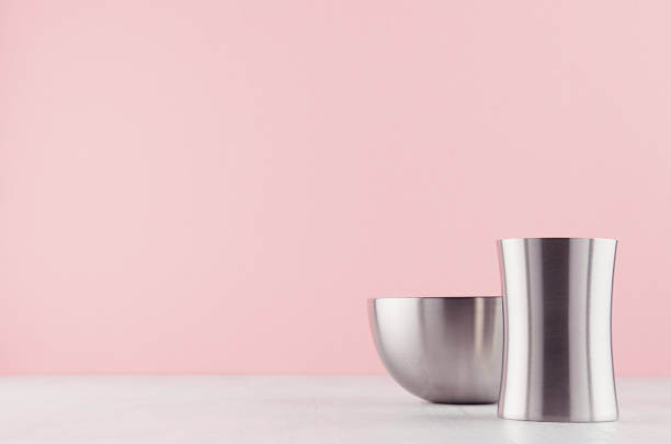 istock Fashioned home interior with rounded polished steel vases different form on white wood table and pastel pink wall. 1162964216