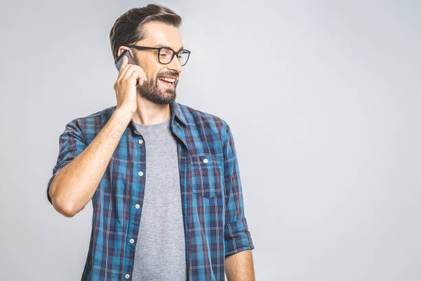 oh, great news! smiling young casual man talking on the phone on the grey background. isolated. - made man object imagens e fotografias de stock