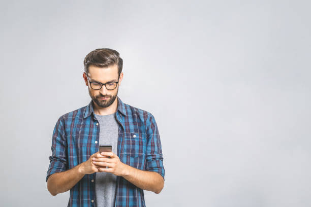 istock Happy young man in glasses typing sms on gray background 1162968740
