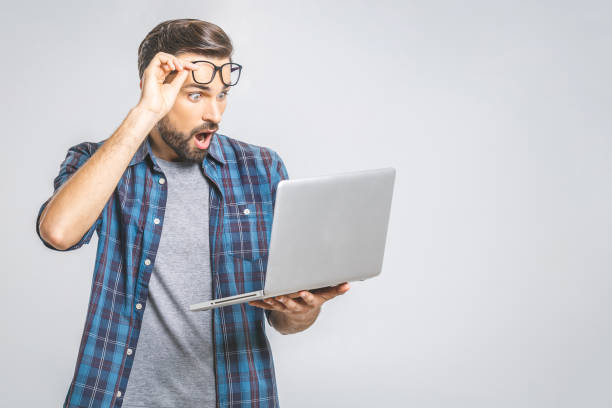 wtf?! omg! oh nein! jung erstaunt emotionale brunet mit borsten mit traurigen grimassen blick auf bildschirm des geräts, kann er nicht glauben, die schlechte nachricht, die er erhielt, gestikulieren mit handflächen der arme. - gasping stock-fotos und bilder