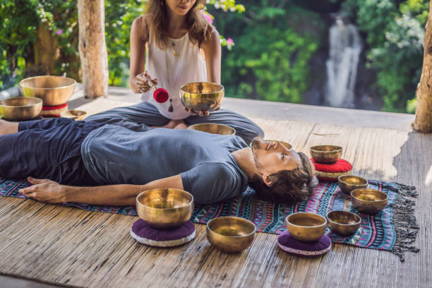 istock Nepal Buddha copper singing bowl at spa salon. Young beautiful man doing massage therapy singing bowls in the Spa against a waterfall. Sound therapy, recreation, meditation, healthy lifestyle and body care concept 1162970135