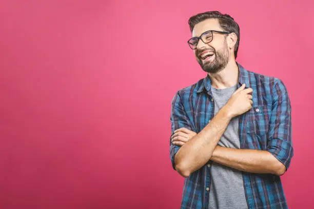 Photo of Portrait of a handsome casual man who laughs, standing and laughing over pink background