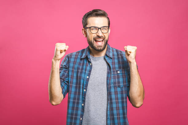 istock Yeah! Happy winner! Happy young handsome man gesturing and keeping mouth open while standing against pink background. 1162970210
