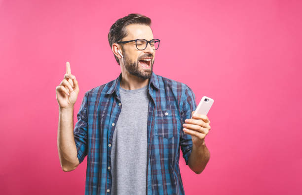 istock Time to relax. Handsome young man in headphones keeping eyes closed while dancing. Over pink background. Isolated. 1162970295