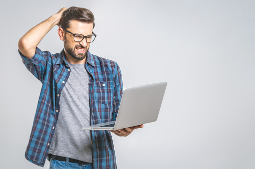 An amazed young man has got a software error. Isolated on grey background.