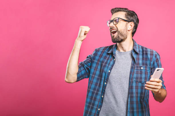 istock Time to relax. Handsome young man in headphones keeping eyes closed while dancing. Over pink background. Isolated. 1162970424