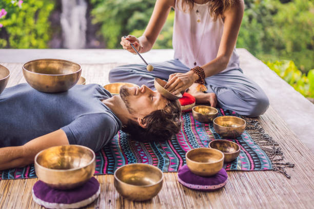 istock Nepal Buddha copper singing bowl at spa salon. Young beautiful man doing massage therapy singing bowls in the Spa against a waterfall. Sound therapy, recreation, meditation, healthy lifestyle and body care concept 1162970443