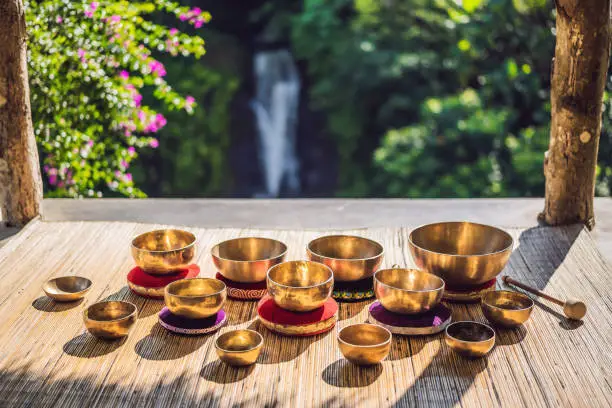 Tibetan singing bowls on a straw mat against a waterfall.