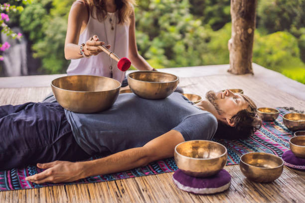 istock Nepal Buddha copper singing bowl at spa salon. Young beautiful man doing massage therapy singing bowls in the Spa against a waterfall. Sound therapy, recreation, meditation, healthy lifestyle and body care concept 1162973394