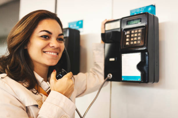 Woman using public telephone Woman using telephone pay phone on the phone latin american and hispanic ethnicity talking stock pictures, royalty-free photos & images