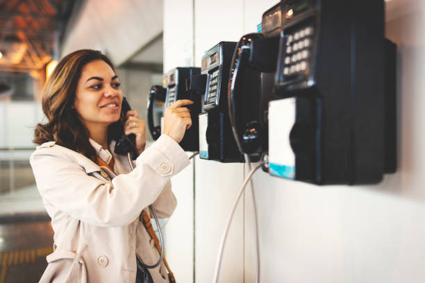 Woman using public telephone Woman using telephone pay phone on the phone latin american and hispanic ethnicity talking stock pictures, royalty-free photos & images