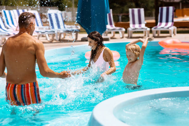 istock Son and parents splashing water while having fun in pool 1162974528