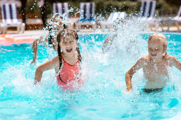 istock Children laughing while splashing water in swimming pool 1162974529