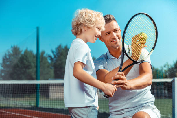istock Father showing his cute curly son tennis ball before playing 1162974842
