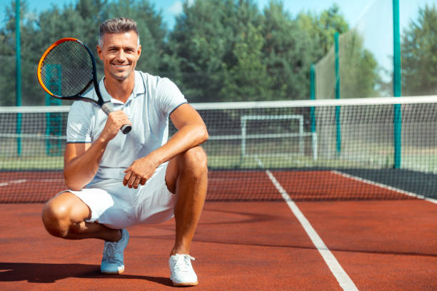 wesoły atletyczny mężczyzna uśmiechnięty po treningu na korcie tenisowym - businessman exercising training muscular build zdjęcia i obrazy z banku zdjęć