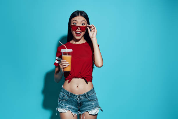 istock Surprise! Attractive young Asian woman smiling while standing against blue background 1162975029