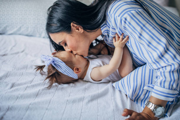 istock Young mom kissing a baby on bed 1162976380