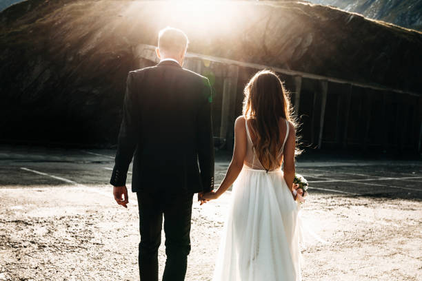 irriconoscibile coppia sposata che cammina tenendosi per mano contro il tramonto dal retro. - 7292 foto e immagini stock