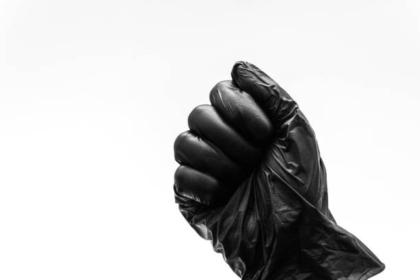 Female hands in black gloves show gestures, signs and symbols isolated on white background. All fingers clenched into a fist. Aggression or hit, game stone. stock photo