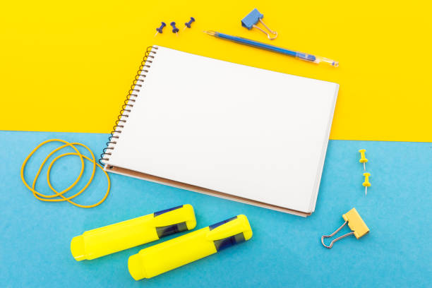 istock Notepad with pen and clip on yellow blue background 1162983494