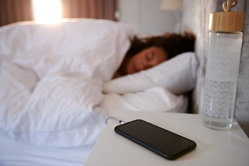 Mujer dormida en la cama con teléfono móvil en la mesa de noche photo