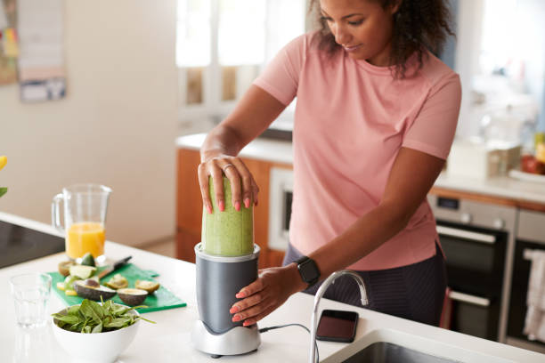 frau macht gesunde saft trinken mit frischen zutaten in elektrischen entsafter nach dem training - juicer food and drink healthy eating sport stock-fotos und bilder