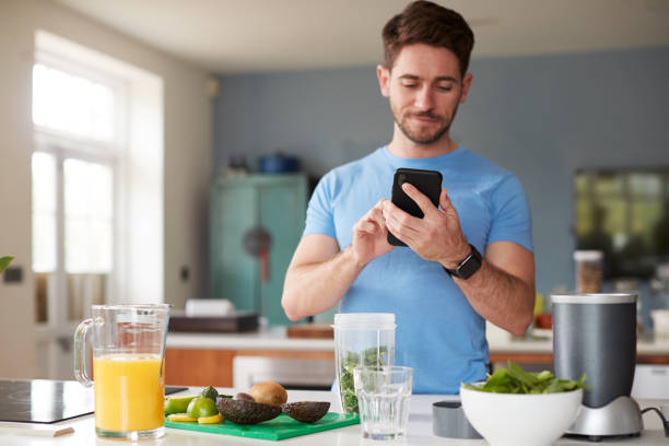 istock Man Using Fitness Tracker To Count Calories For Post Workout Juice Drink He Is Making 1162988168