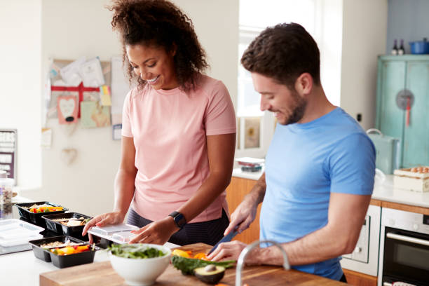 couples préparant le lot des repas sains à la maison dans la cuisine ensemble - healthy eating sport exercising women photos et images de collection