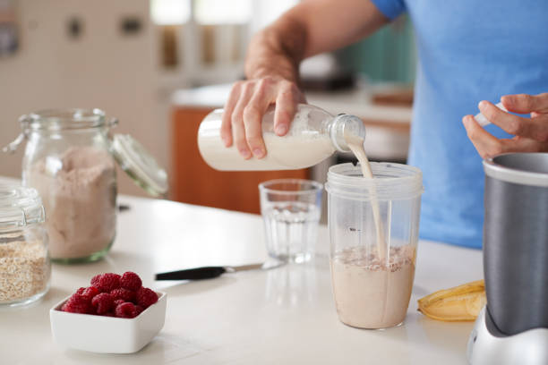 fermez-vous vers le haut de l'homme faisant le shake de protéine après l'exercice à la maison - protein photos et images de collection