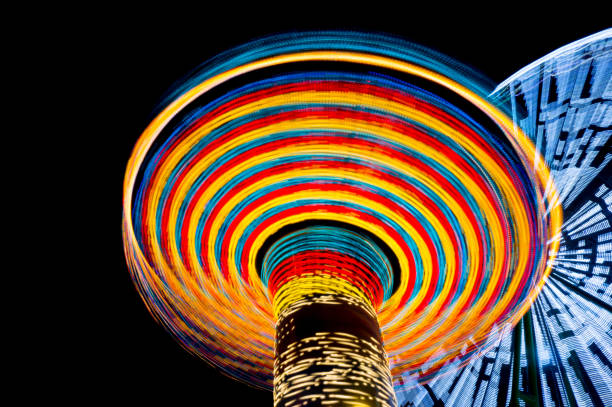 夜の遊園地のカルーセルと観覧車、長時間露光。スピードの概念。 - ferris wheel wheel blurred motion amusement park ストックフォトと画像