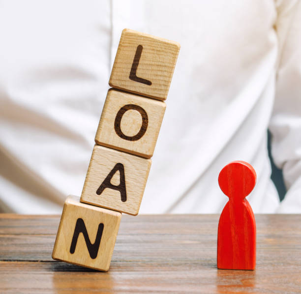 Wooden blocks with the word Loan fall on a miniature person. The concept of large lending rates for property and business. Lending market. Bank, commercial and consumer credit. Real estate bloques de madera con la palabra préstamo caen sobre una persona en miniatura. el concepto de grandes tipos de interés de préstamo para la propiedad y los negocios. mercado de préstamos. crédito bancario, comercial y al consumo. inmobiliaria