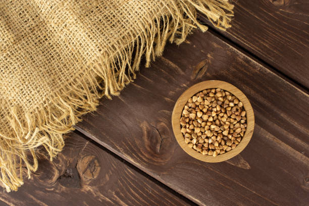 raw buckwheat grain on brown wood - achene imagens e fotografias de stock