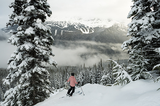 Skiing fresh powder in Whistler, Canada. A women skiing solo in the mountains.