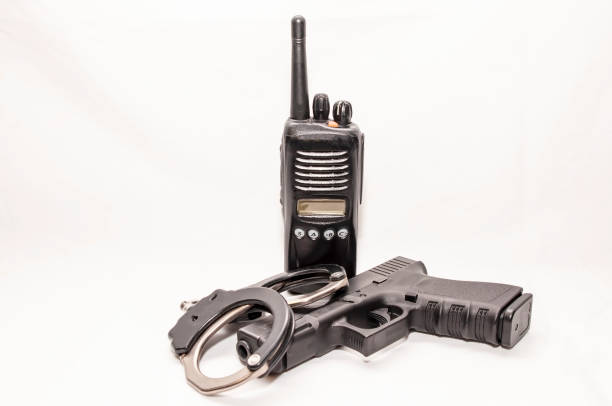 a set of black and silver handcuffs with a black 9mm pistol in front of a police radio - american justice audio imagens e fotografias de stock