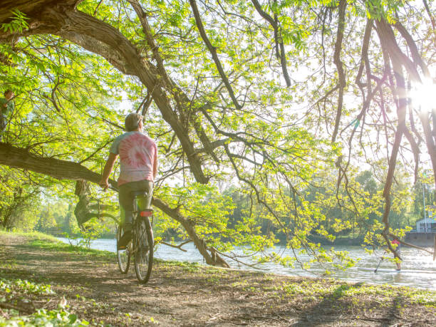 istock Man rides along the river on a bicycle 1163008474