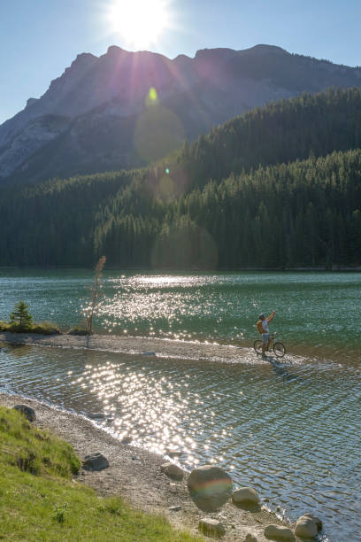 istock Mountain biker rides along sandy spit in mountain lake 1163008538