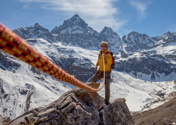 Climbing rope leads to mountain guide on rock summit