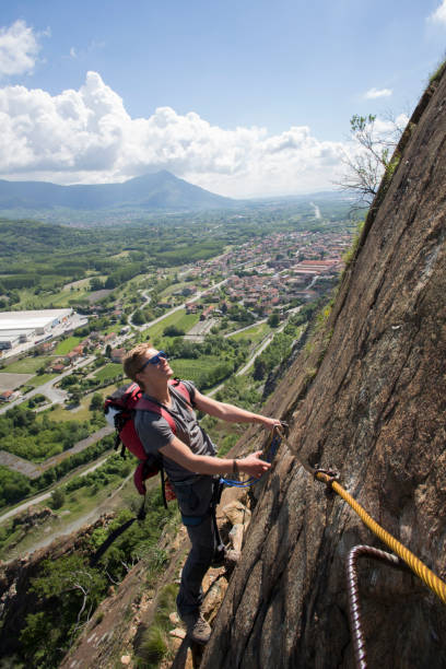l'alpiniste fait son chemin vers le haut de la paroi rocheuse - mountain climbing rock climbing motivation awe photos et images de collection