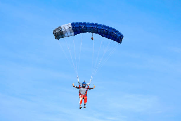 istock Skydiver with a dark blue parachute on the background a blue sky 1163011861