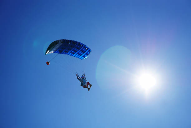 istock Skydiver with a blue parachute close up under sunshine 1163013209