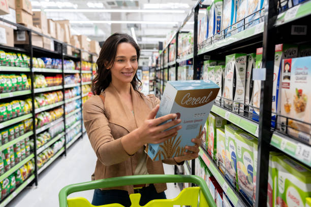 piękna młoda kobieta wybierająca płatki z półki na zakupy spożywcze w supermarkecie - cereal product zdjęcia i obrazy z banku zdjęć